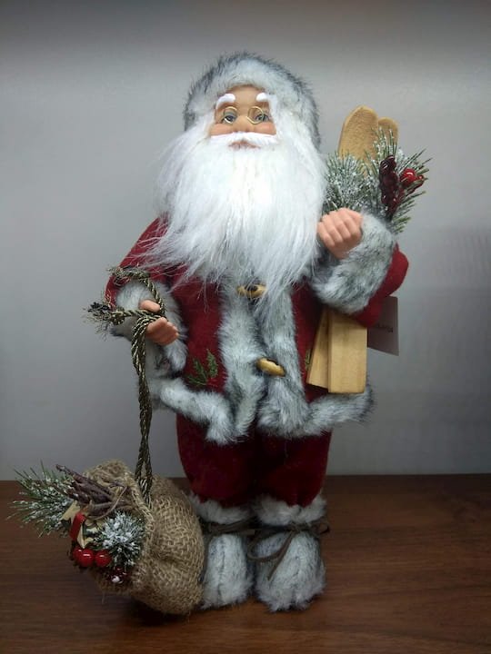 Фигура Санта Клауса в красной шубе с лыжами и мешком подарков